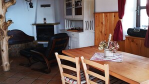 Un coin repas rustique avec une table et des chaises en bois, un buffet aux portes vitrées et un luminaire suspendu.