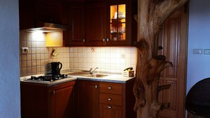 Une cuisine avec des meubles en bois, un dosseret carrelé, une cuisinière à gaz et une structure originale en bois en forme d’arbre.