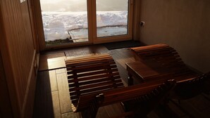 Une pièce dotée d’un plancher en bois, d’un banc et d’une grande fenêtre offrant une vue sur des montagnes enneigées.