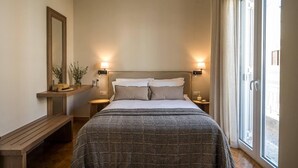 A bedroom with a large bed, bedside lamps, a bench, and a window with curtains. - Sofia's Lemontree 3-bed House in Agios Nikolaos (Agios Nikolaos)