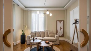 A modern living room with a sofa, two coffee tables, a floor lamp, and a painting on the wall. - Sofia's Lemontree 3-bed House in Agios Nikolaos (Agios Nikolaos)