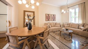 A modern living room with a round wooden dining table, beige sofas, and a coffee table. - Sofia's Lemontree 3-bed House in Agios Nikolaos (Agios Nikolaos)
