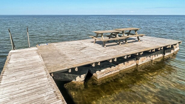 Un muelle de madera que se extiende sobre aguas tranquilas, con una mesa de picnic al final.