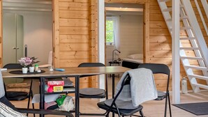Un interior de madera con zona de comedor, sillas, mesa y una escalera.