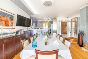 Un grand espace dédié à la salle à manger, avec une longue table, des chaises et une cuisine en arrière-plan.