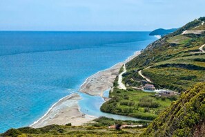 Un paysage côtier avec une route sinueuse, une plage et quelques bâtiments.