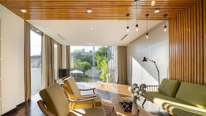Una sala de estar moderna con un sofá verde, dos sillones, una mesita de centro y un televisor.