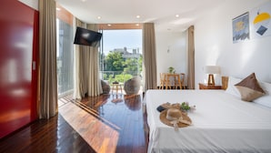 Habitación de hotel con una cama grande, televisión, balcón con vistas a la ciudad y zona de comedor.