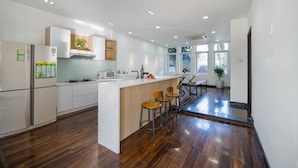 Una cocina moderna con armarios blancos, una isla de madera con taburetes altos y un microondas integrado, además de un ventanal que proporciona luz natural.