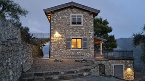 Una casa de piedra con un balcón y una escalera de piedra que lleva a la entrada.
