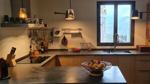 Una cocina moderna con un ventanal grande, horno empotrado y diversos utensilios de cocina.