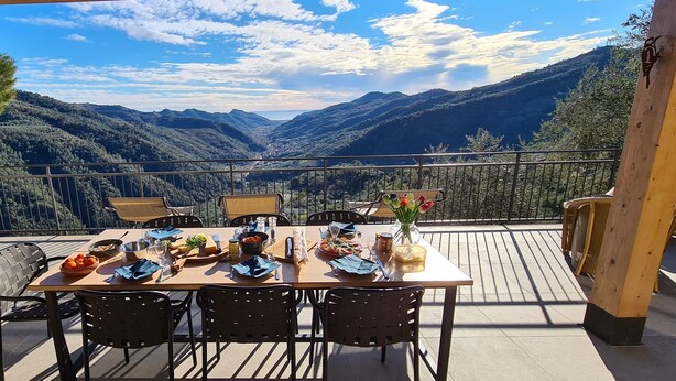Mesa de comedor al aire libre con una vista panorámica de montañas.