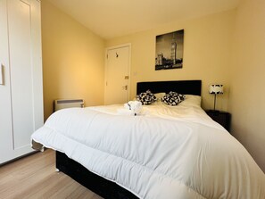 Een net opgemaakt bed met witte beddengoed, een zwart hoofdbord en twee zwart-wit gestreepte kussens.