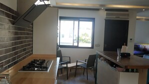 Cozinha moderna com fogão a gás, forno embutido, uma janela grande e área de jantar com cadeiras.