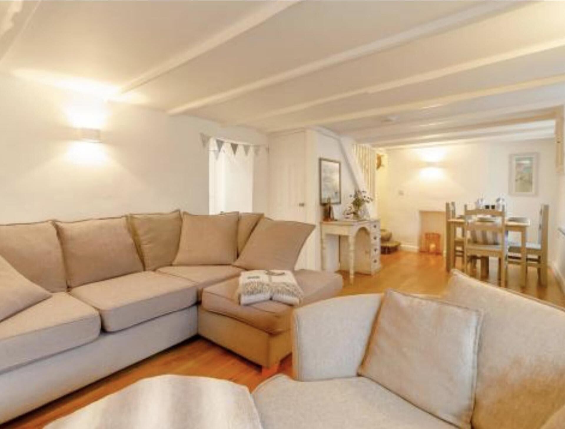 Una sala de estar acogedora con un amplio sofá en forma de L, una mesita y un comedor con sillas de madera.