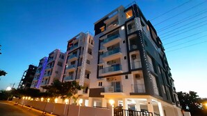 A multi-story residential building with balconies, a gated entrance, and decorative lighting. - Senri By Yuhi (Tada)