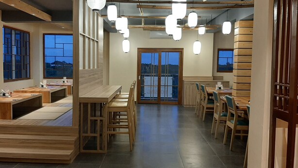 A modern restaurant with wooden furniture, large windows, and hanging pendant lights. - Senri By Yuhi (Tada)