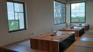A conference room with tatami mats, a long wooden table, and large windows with a city view. - Senri By Yuhi (Tada)