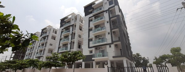 A multi-story residential building with balconies, a gated entrance, and a clear sky. - Senri By Yuhi (Tada)