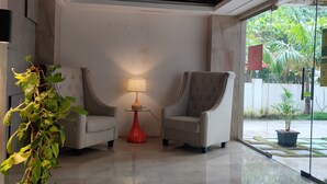 A modern lobby with two armchairs, a red lamp, and a potted plant. - Senri By Yuhi (Tada)