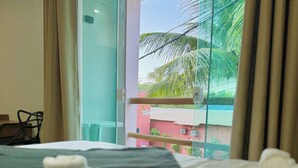 Una habitación de hotel con cama, vistas a palmeras y un balcón.