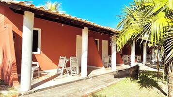 A building with a red exterior, white columns, and a covered patio area with chairs and tables.