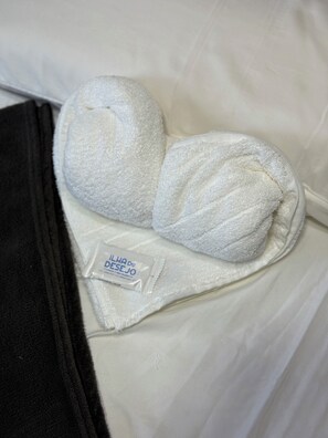 A hotel bed with a white pillow and a white towel placed on it. - Pousada Ilha do Desejo (Una)