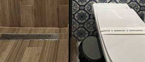 A bathroom with a shower, toilet, and a tiled wall with a geometric pattern.