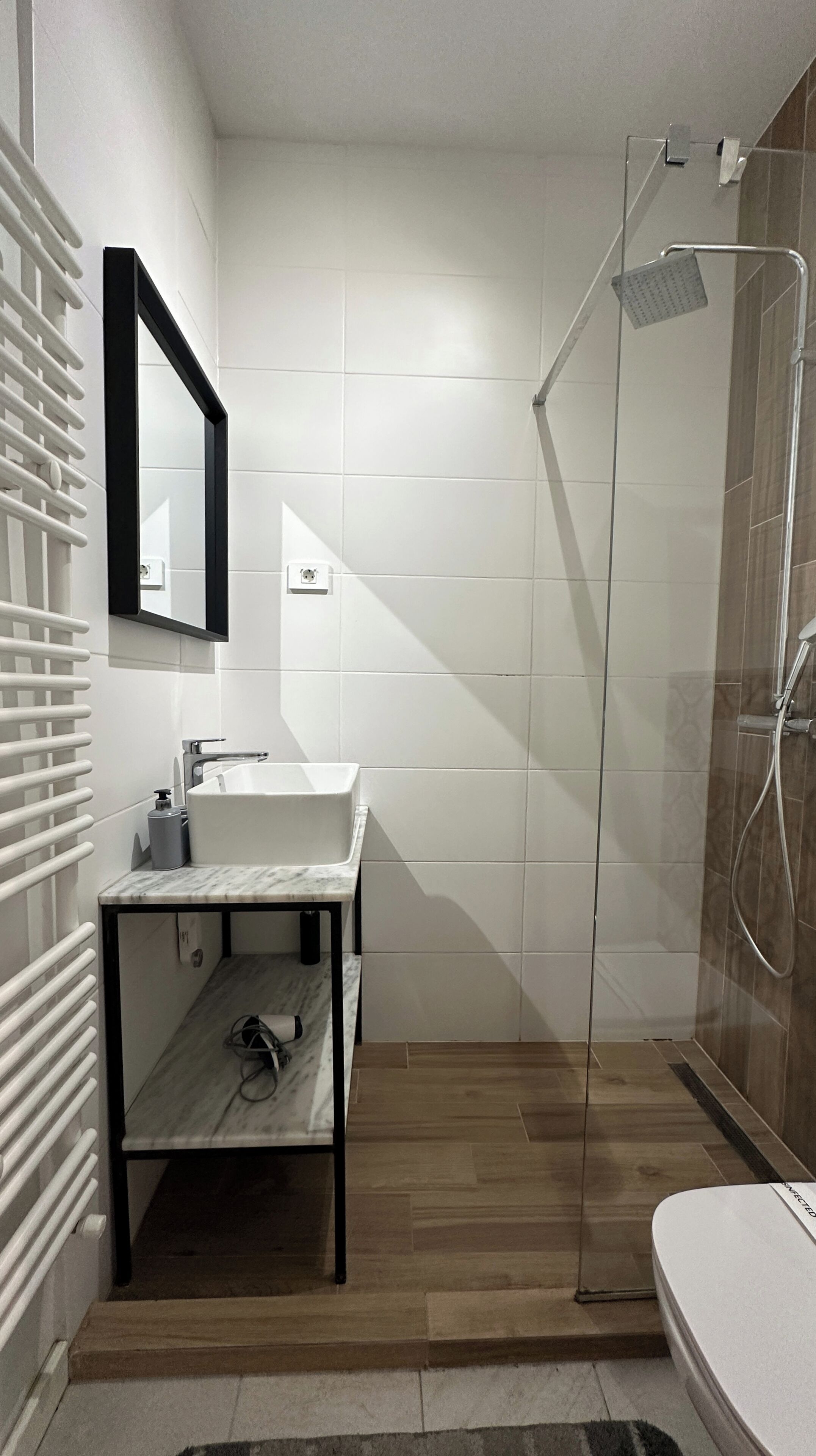 A modern bathroom with a white sink, mirror, and shower.