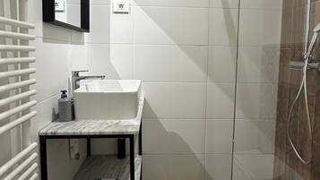 A modern bathroom with a white sink, mirror, and shower.