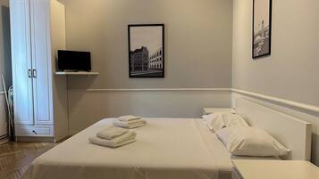 Habitación de hotel con cama, televisión en un estante y un cuadro en la pared.