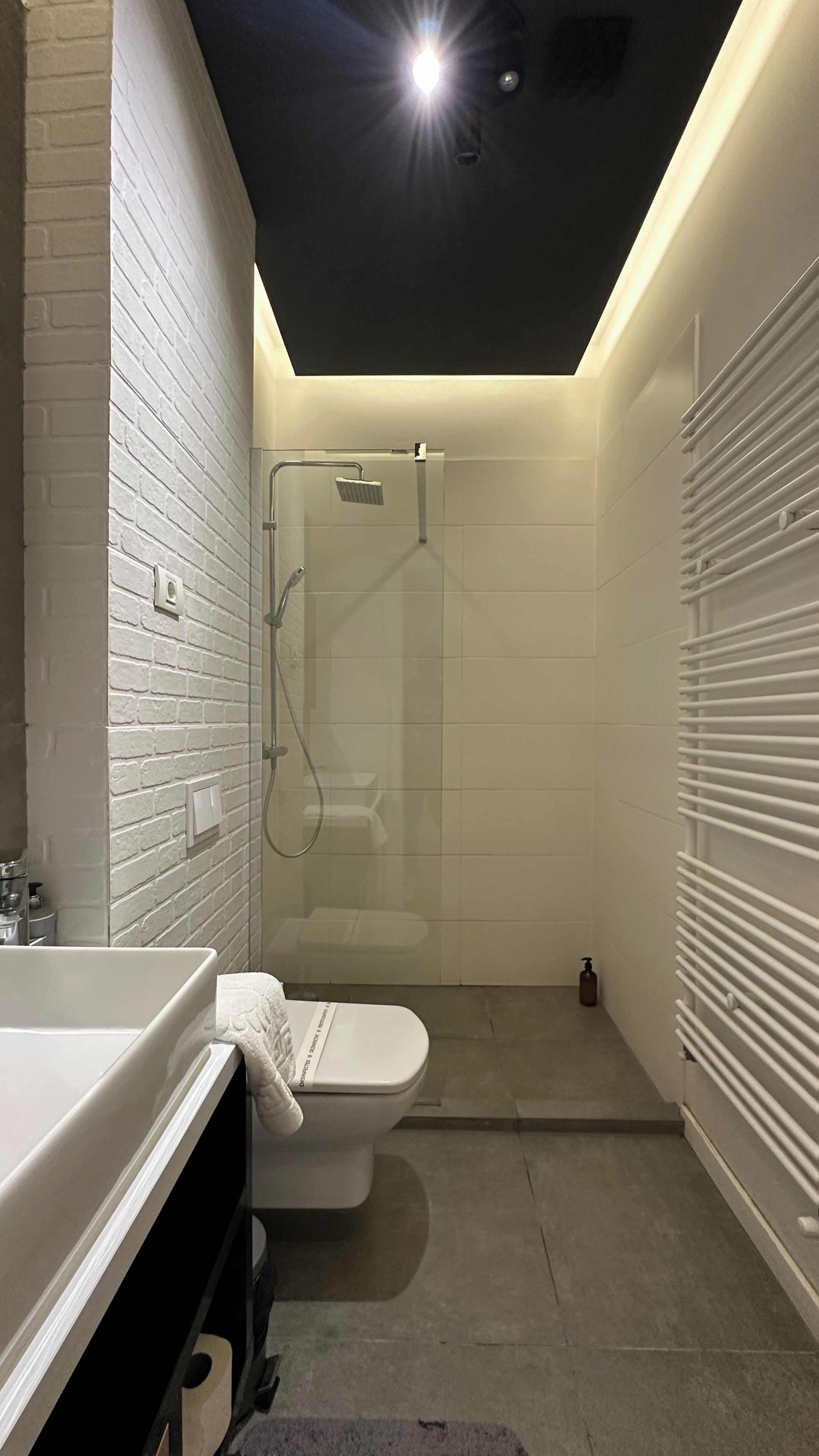 A modern bathroom with a glass shower enclosure, a white toilet, and a sink with a towel.