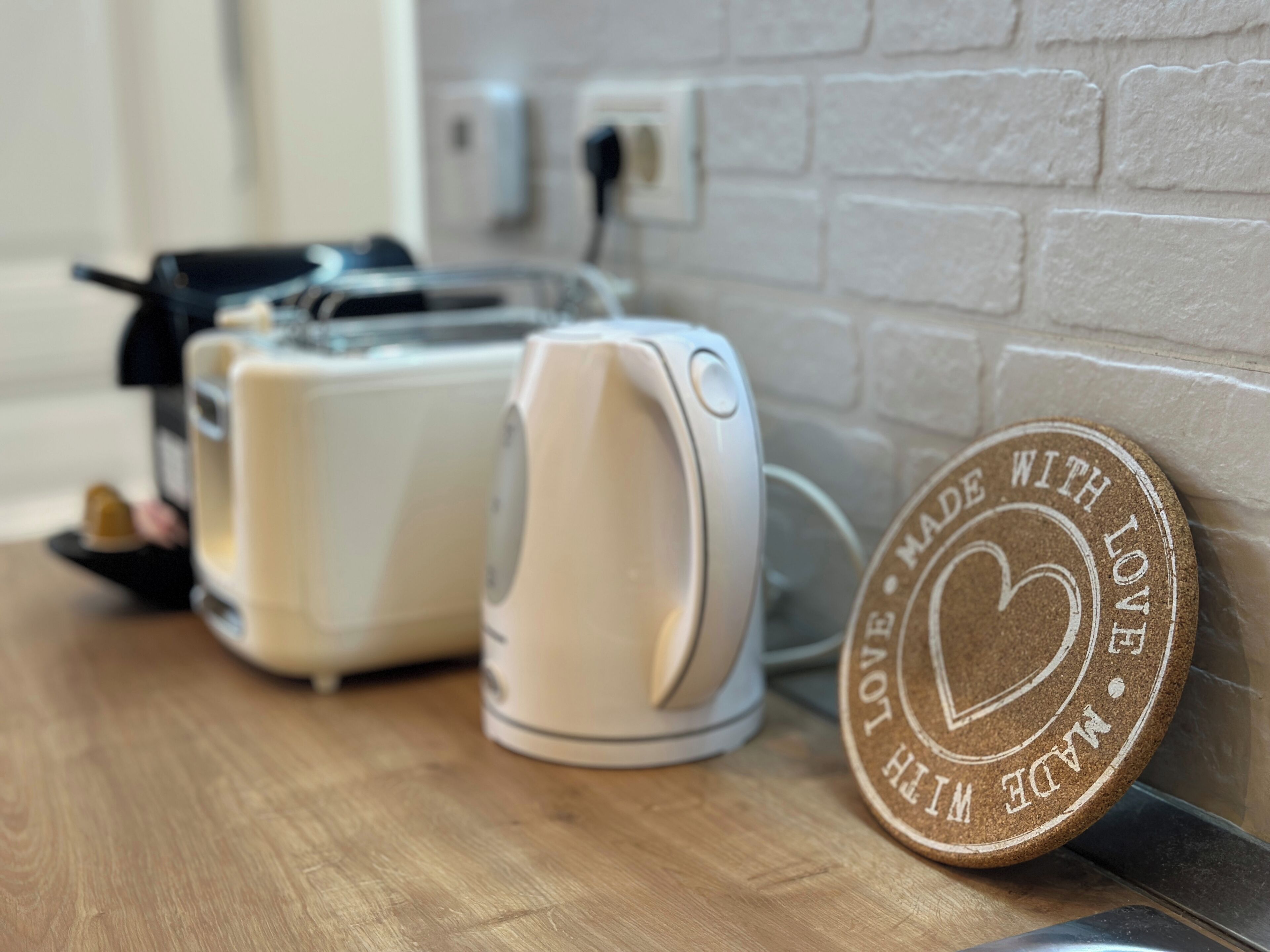 A kitchen counter with a toaster and a kettle, and a cork coaster with the text "MADE WITH LOVE MADE WITH LOVE".