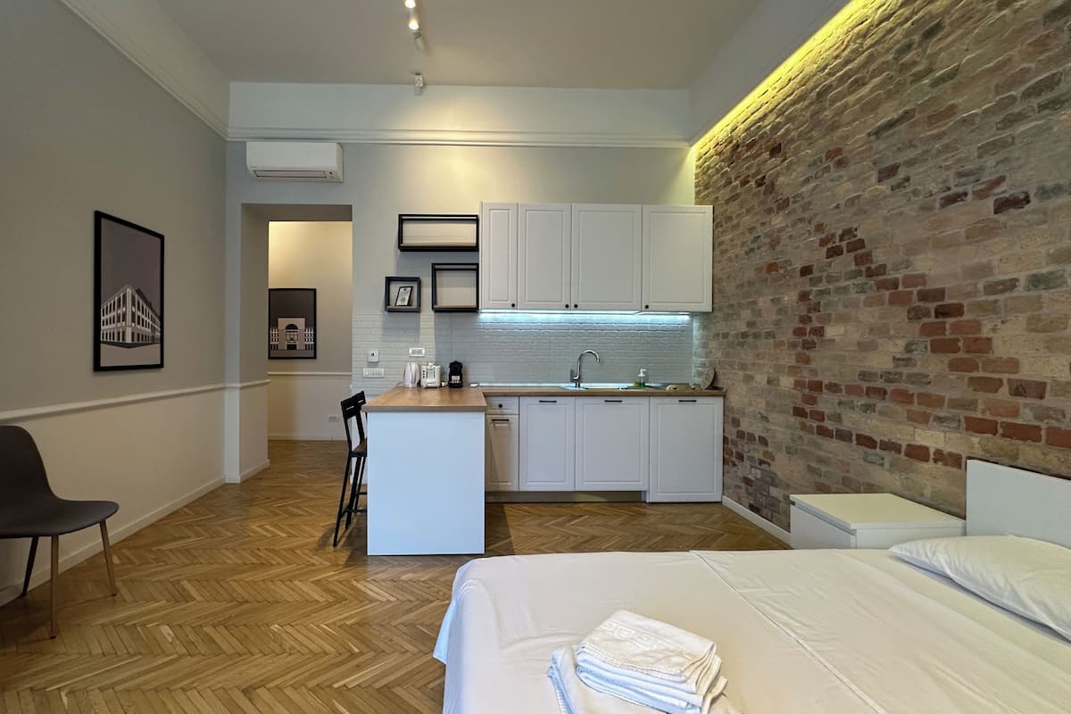 Habitación de hotel compacta con kitchenette, una cama, una silla y un pequeño comedor.