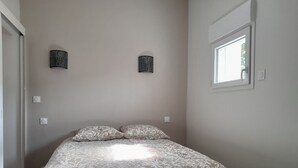 A bedroom with a bed, two wall-mounted lamps, a window, and a door. - Maison Chaleureuse au Calme Proximités Commodités (Montaigu-Vendée)