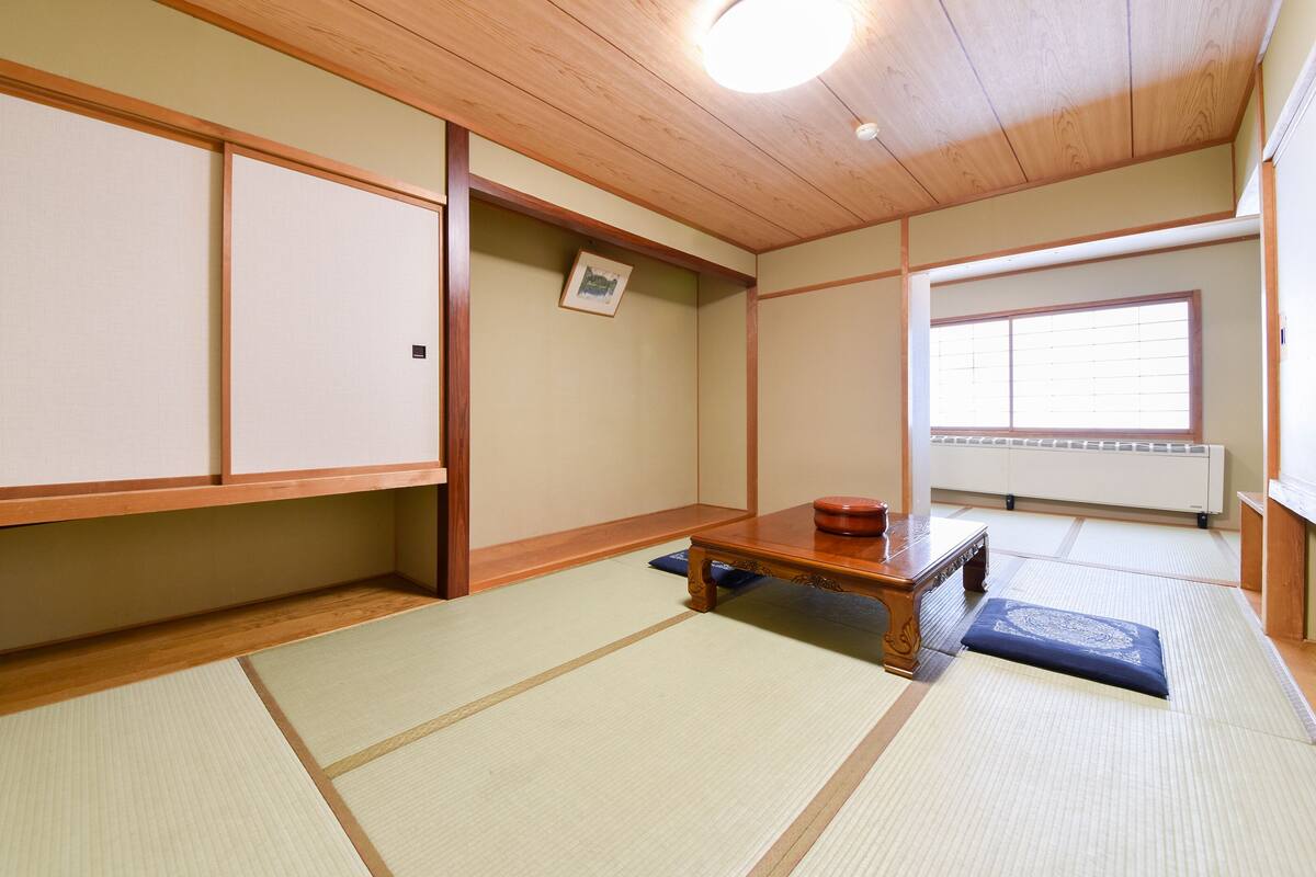 Ein traditioneller japanischer Raum mit Tatami-Böden, einem niedrigen Holztisch und verschiebbaren Türen.