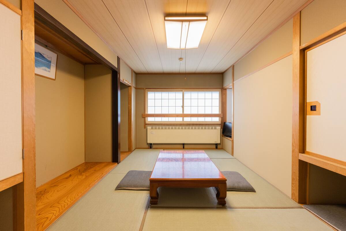 Ein traditioneller japanischer Raum mit Tatami-Böden, einem niedrigen Holztisch und verschiebbaren Türen.