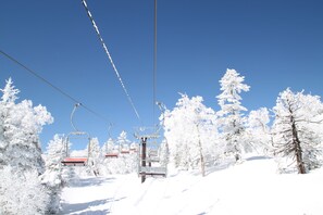 Een skilift met een helderblauwe lucht en sneeuwbedekte bomen.