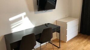 A small room with a desk, two chairs, a television mounted on the wall, and a white cabinet. - Årsta Stockholm Aparment 339 (Arsta)