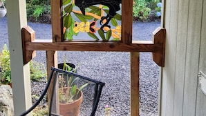 Eine hölzerne Pergola mit einem Buntglasfenster, das einen Vogel inmitten von Blättern zeigt.