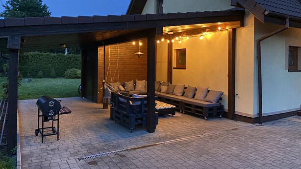 A covered outdoor seating area with a grill, a bench, and string lights. - Nice place to stay near Pszczyna (Goczalkowice Zdroj)