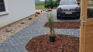 Un camino pavimentado que lleva a una puerta de madera, con un vehículo estacionado al fondo.