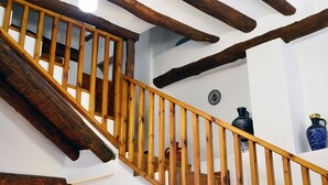 Un escalier en bois avec des poutres apparentes et un mur blanc orné d’une plaque décorative.
