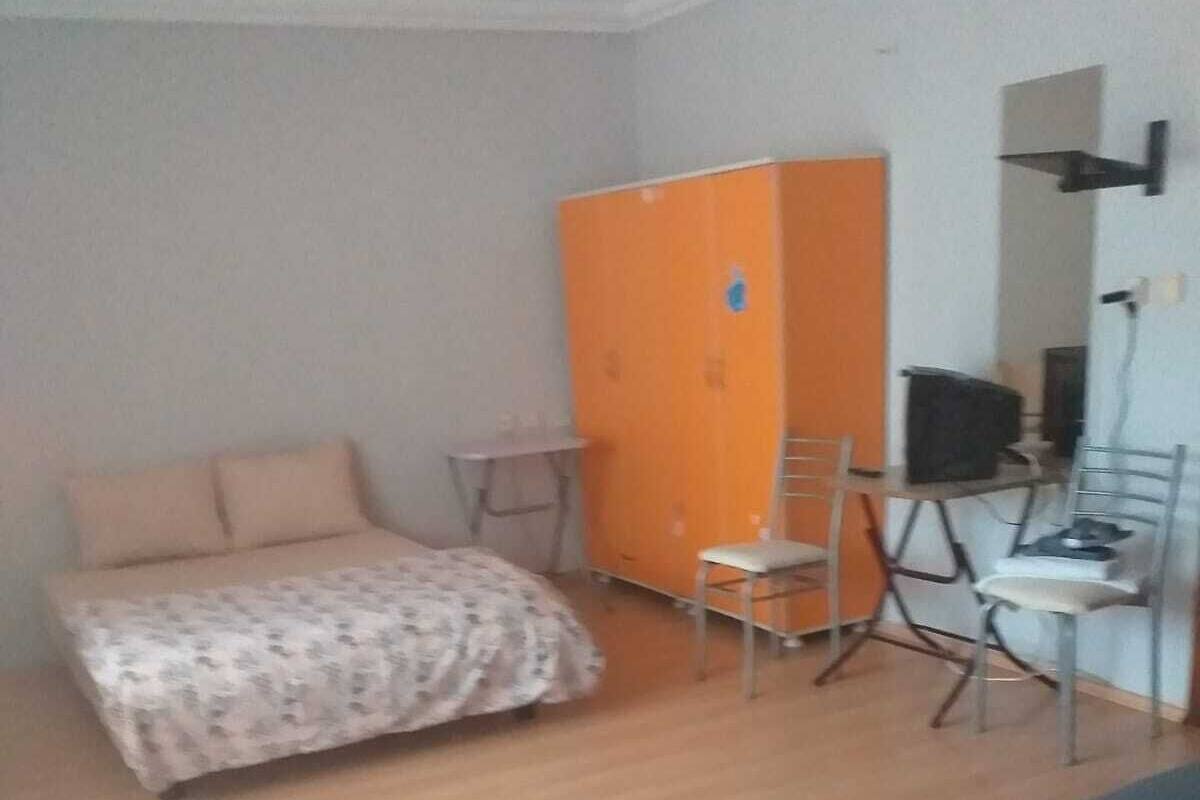 Un dormitorio con una cama, un escritorio, una silla y un armario naranja.