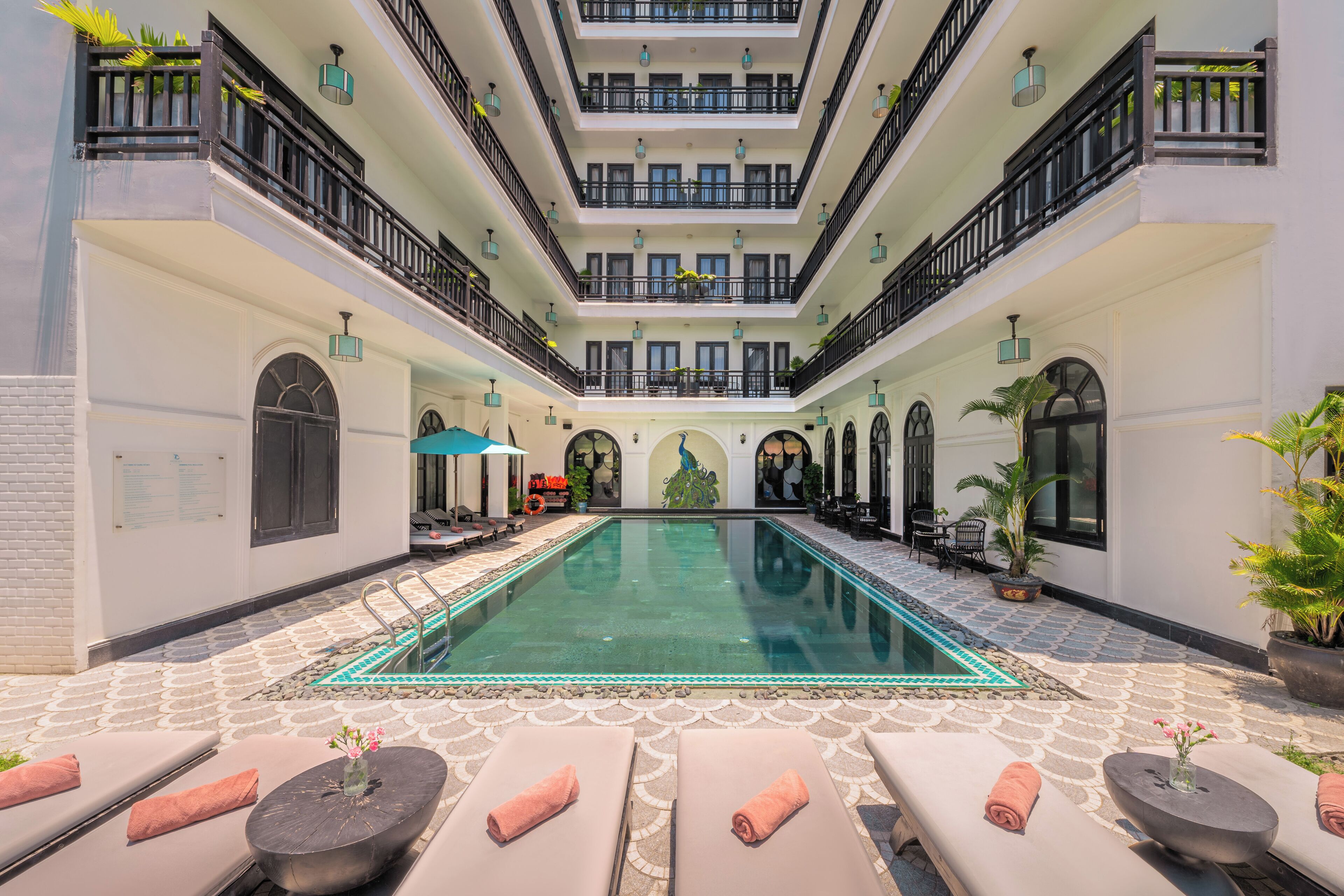 A multi-level indoor swimming pool with lounge areas and potted plants.