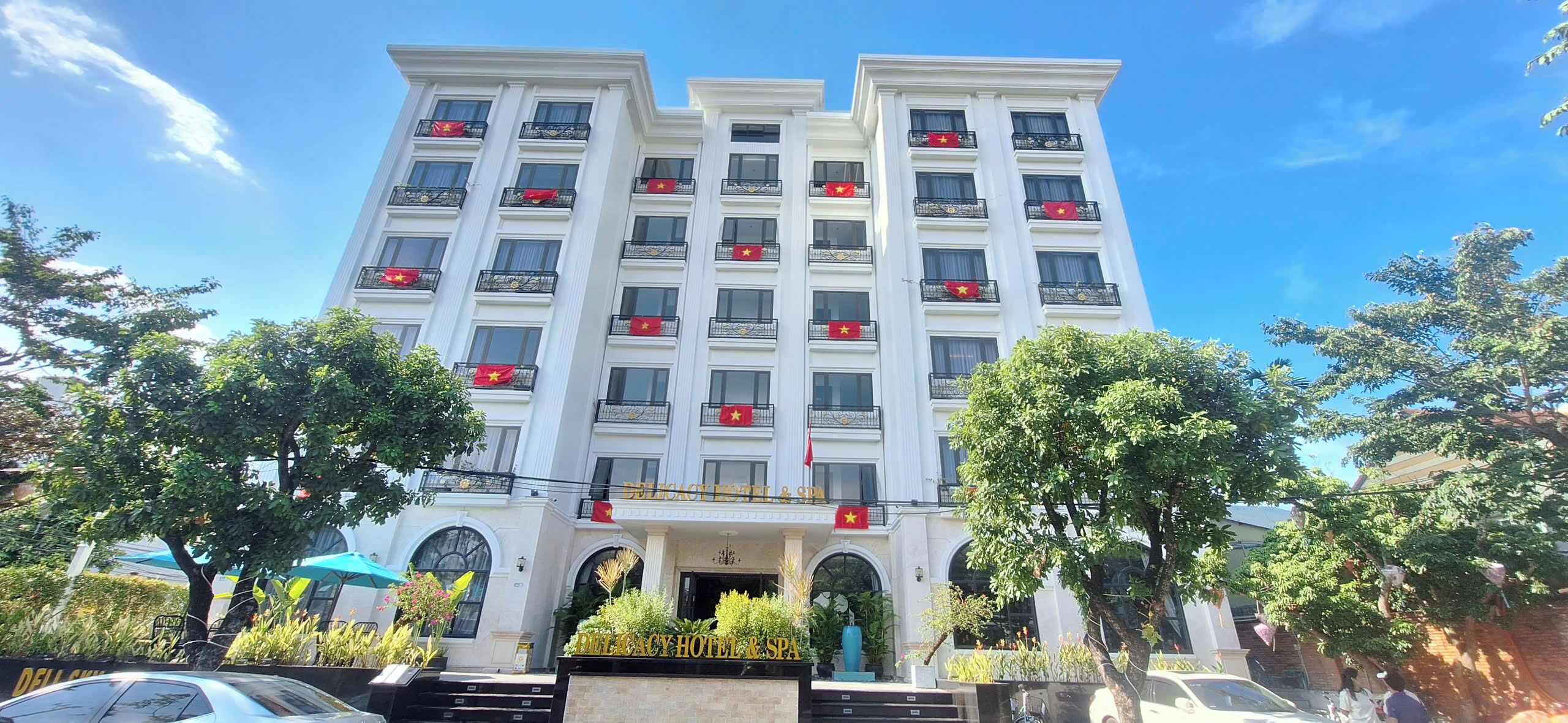 Ein mehrstöckiges Hotel mit Balkonen, einem zentralen Eingang und einer Flagge auf jedem Balkon.