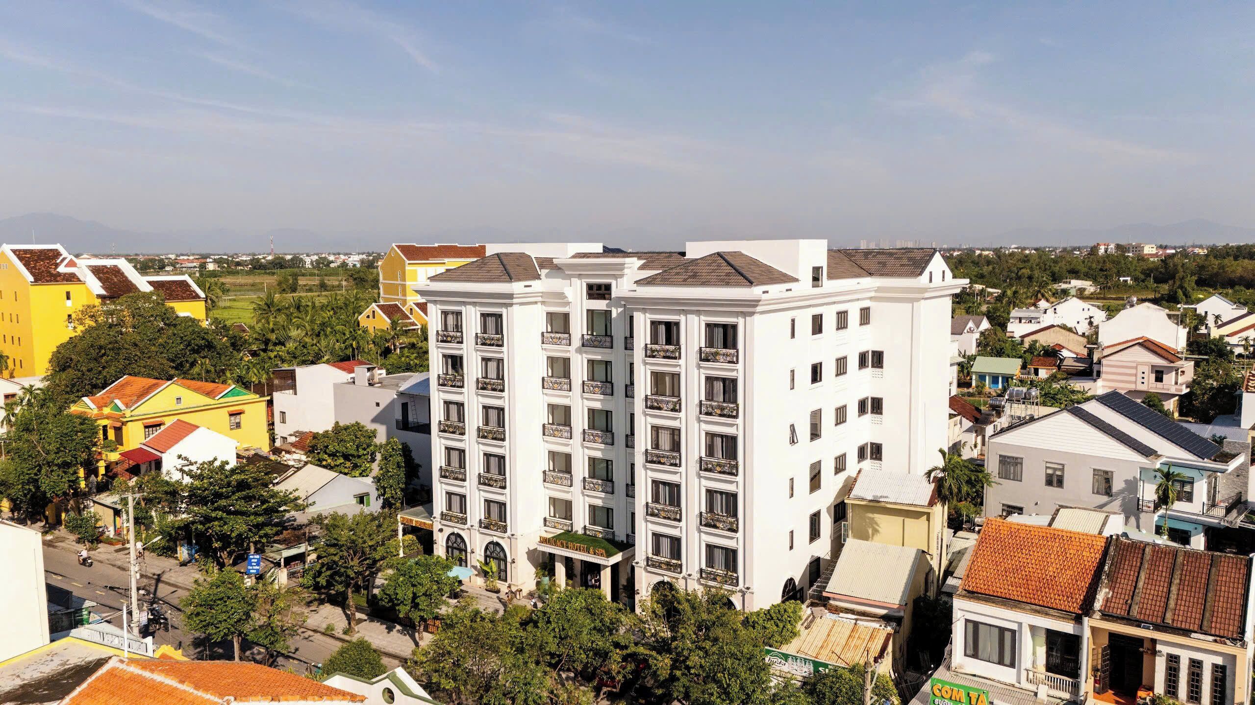 A multi-story hotel with balconies, surrounded by colorful buildings and greenery.