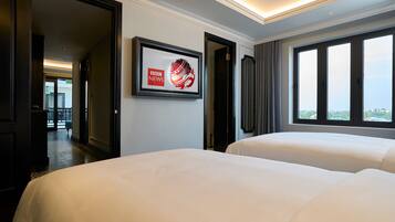 A hotel room with two beds, a framed picture on the wall, and a window with a view.