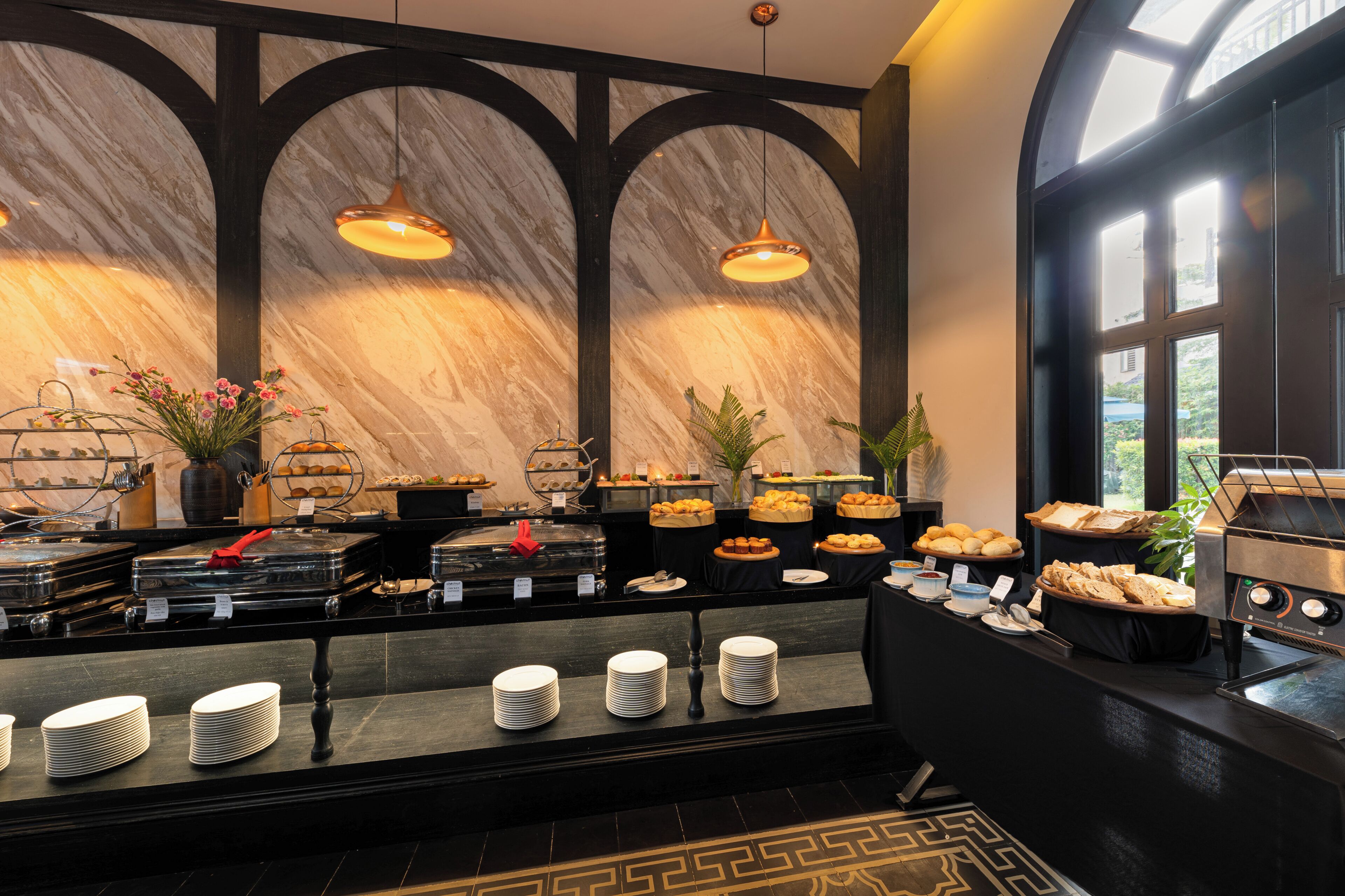 A buffet area with marble walls, pendant lighting, and a variety of food items.