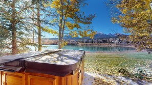 Een hottub in een natuurlijke omgeving, met uitzicht op een meer en bergen.
